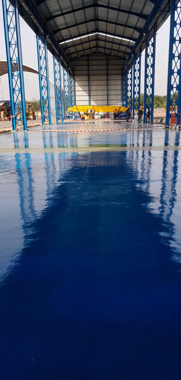 Halle à charpente métallique, sol résine bleu miroir
